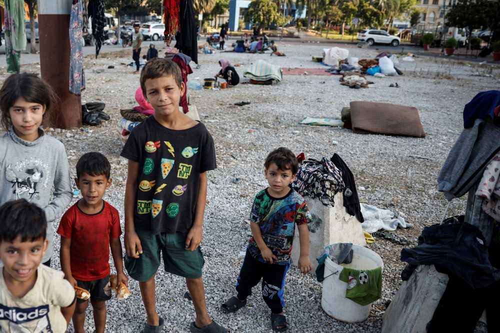 Displaced children pose at a gravel lot, where their families took temporary shelter, in Beirut. — Reuters 