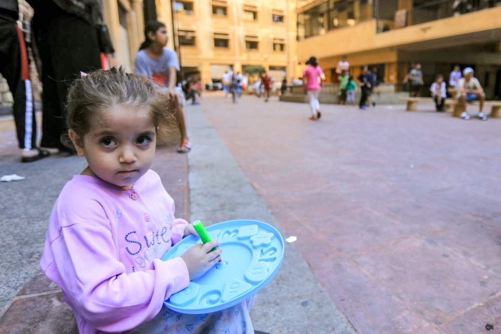 A girl looks on as she sits in the courtyard of the Azariyeh building complex in central Beirut, 