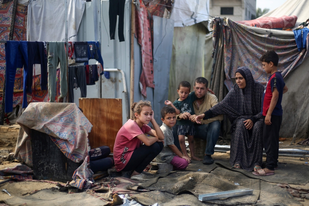 Palestinians sit at the site of an Israeli airstrike which hit tents for displaced people, in the central Gaza Strip. — AFP