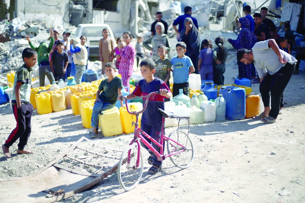 Palestinians queue to fill cans with water near Khan Yunis in the southern Gaza Strip. — AFP