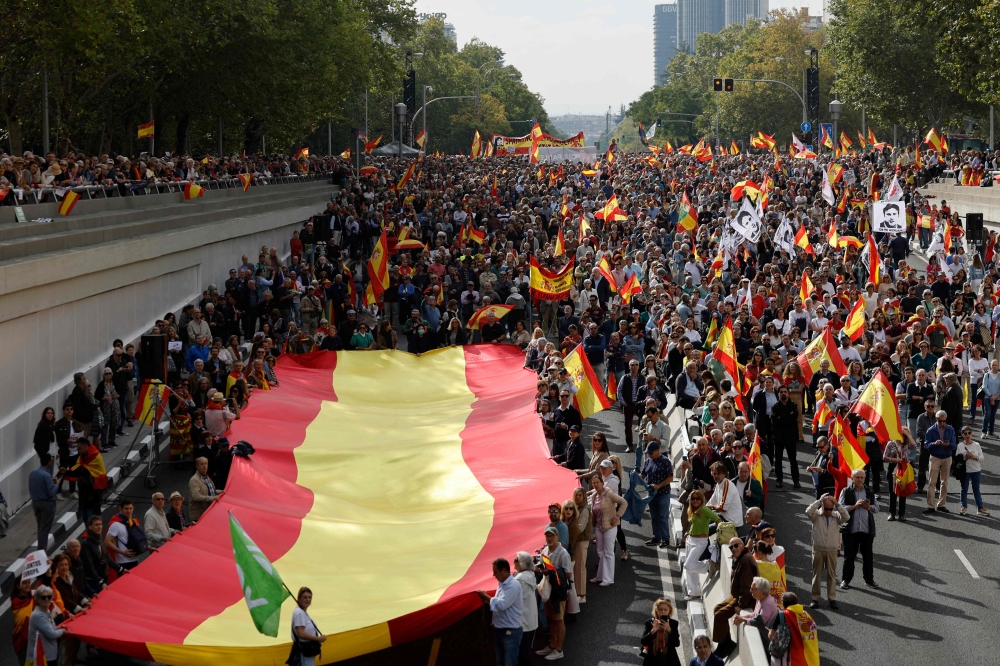 Protesters carry a giant Spanish flag during a demonstration to protest against the ruling government, in Madrid. — AFP