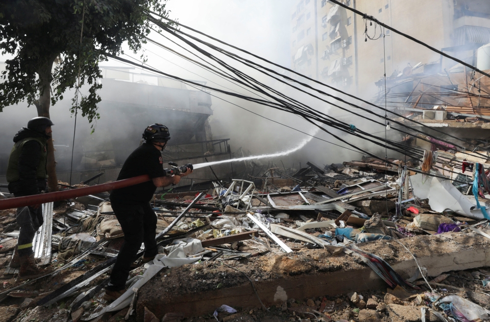 Civil defence members put out a fire at a damaged site, in the aftermath of Israeli strikes on Beirut's southern suburbs. — Reuters 