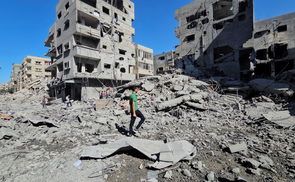 Palestinians gather at the site of Israeli strikes on houses and residential buildings, in Beit Lahiya. — Reuters 