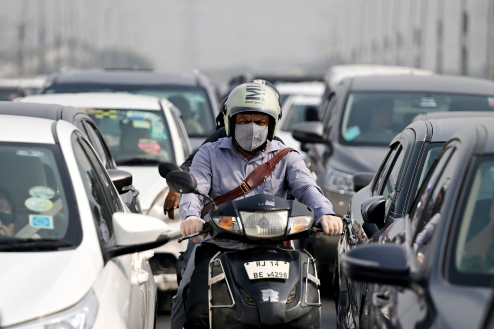 A motorist wears a mask and gloves as he rides his scooter amid smog, in New Delhi