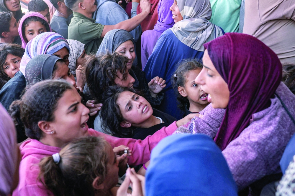 A woman argues with girls as people crowd outside a bakery as they queue for bread in Khan Yunis in the southern Gaza Strip on Wednesday. - AFP