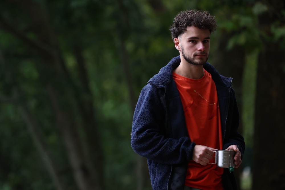 French urban climber Titouan Leduc poses in the forest of Meudon, on October 3, 2024, before climbing the Franklin Tower, a 115-metre-high office skyscraper located in La Defense business district. Leduc, a 23-year-old urban climber from northeastern France, likes to scale skyscrapers without any ropes or specialist equipment, wearing only a pair of climbing boots. (Photo by Anne-Christine POUJOULAT / AFP)

