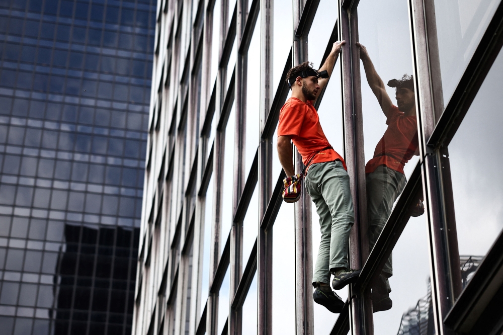 French urban climber Titouan Leduc climbs the Franklin Tower, a 115-metre-high office skyscraper located in La Defense business district, west of Paris, on October 3, 2024. Leduc, a 23-year-old urban climber from northeastern France, likes to scale skyscrapers without any ropes or specialist equipment, wearing only a pair of climbing boots. (Photo by Anne-Christine POUJOULAT / AFP)

