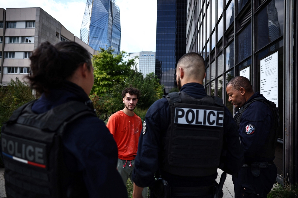 French urban climber Titouan Leduc answers to police officers after climbing the Franklin Tower, a 115-metre-high office skyscraper located in La Defense business district, west of Paris, on October 3, 2024. Leduc, a 23-year-old urban climber from northeastern France, likes to scale skyscrapers without any ropes or specialist equipment, wearing only a pair of climbing boots. (Photo by Anne-Christine POUJOULAT / AFP)

