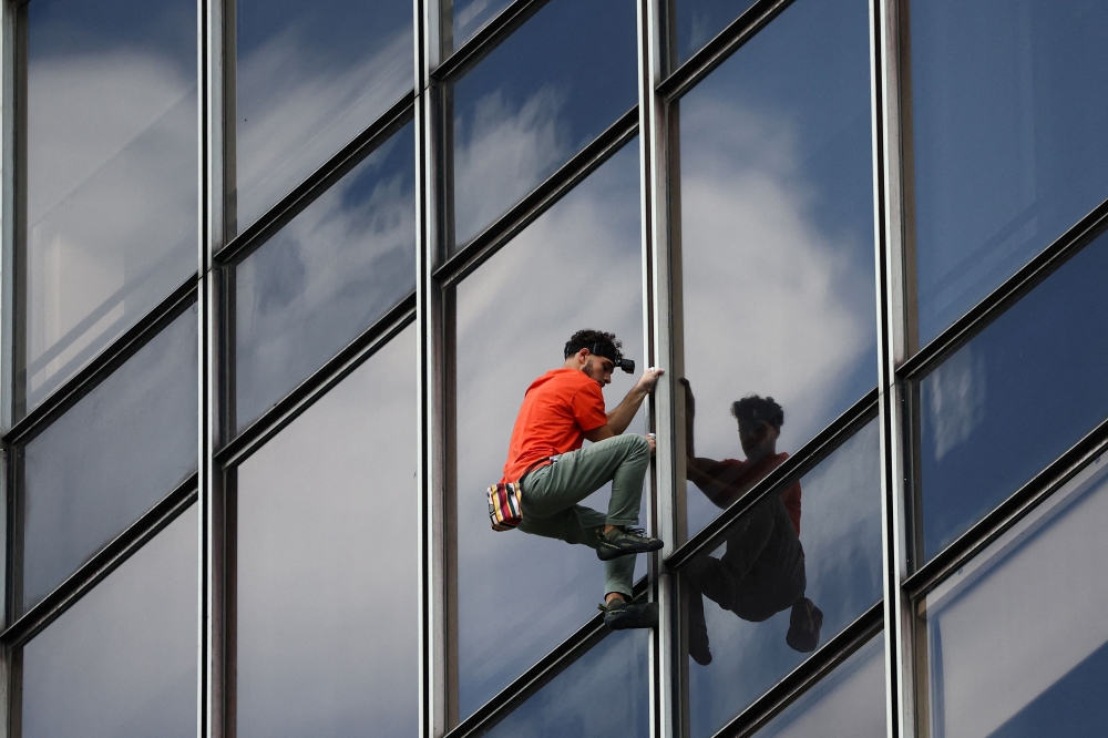 French urban climber Titouan Leduc climbs the Franklin Tower, a 115-metre-high office skyscraper located in La Defense business district, west of Paris, on October 3, 2024. Leduc, a 23-year-old urban climber from northeastern France, likes to scale skyscrapers without any ropes or specialist equipment, wearing only a pair of climbing boots. (Photo by Anne-Christine POUJOULAT / AFP)

