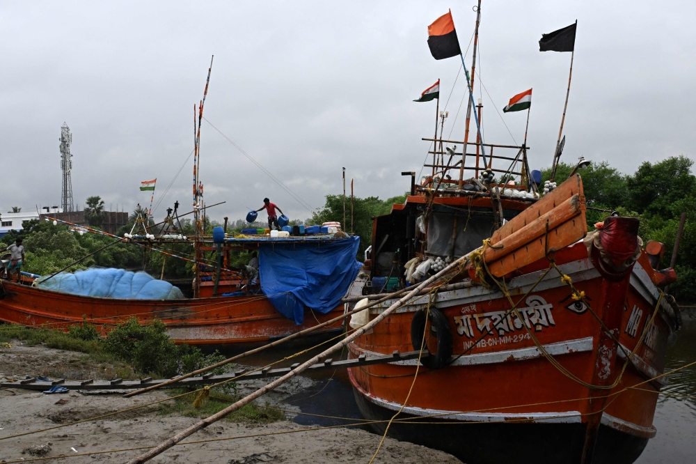 Fishermen work on fishing trawlers parked at a beach near the Bay of Bengal in Digha, around 200km southwest of Kolkata. - AFP