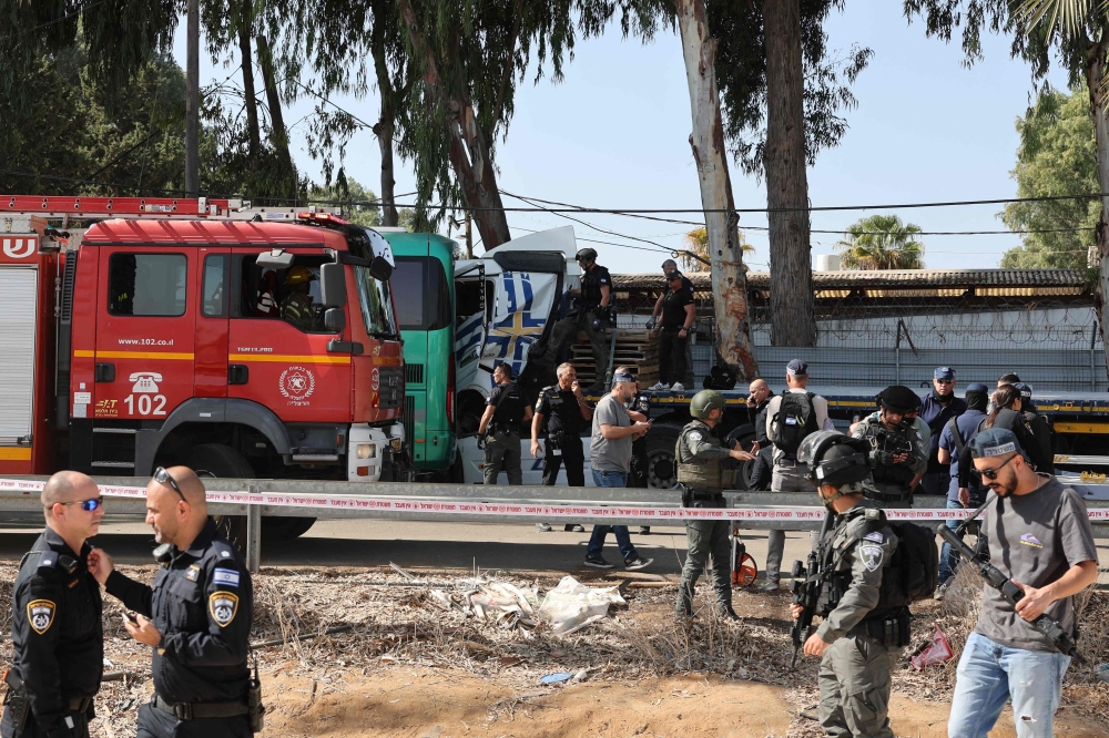 Israeli police and emergency responders secure the truck after a driver rammed his vehicle into a crowd of people at a bus stop in Ramat Hasharon