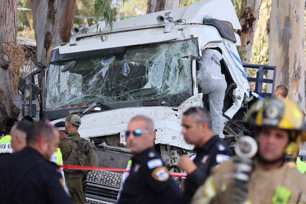 Israeli police and emergency responders secure the truck after a driver rammed his vehicle into a crowd of people at a bus stop in Ramat Hasharon