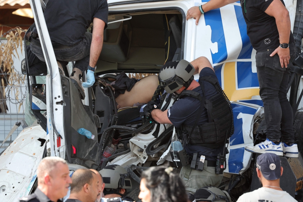 Israeli police and emergency responders secure the truck after a driver rammed his vehicle into a crowd of people at a bus stop in Ramat Hasharon