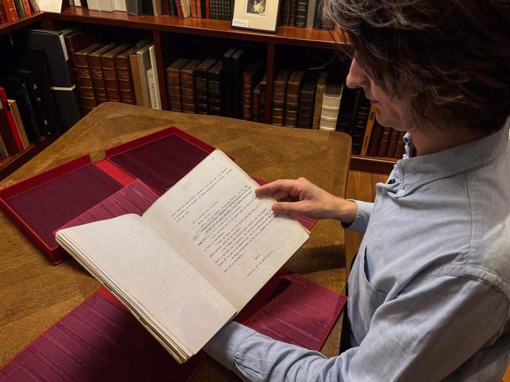 Literature Specialist Sammy Jay of Peter Harrington Rare Books holds a rare carbon typescript of late French writer Antoine de Saint-Exupery's "Le Petit Prince", featuring extensive handwritten corrections and sketches by the author, on October 16, 2024, during the book presentation at the Peter Harrington Rare Books, a London-based rare book dealer. A mysterious black cover damaged by time protects a priceless treasure: the typescript of Antoine Saint-Exupery's "Le Petit Prince", the only one to have belonged to the writer, is being offered for sale by Peter Harrington Rare Books. Accompanied by its passport, issued by the French Ministry of Culture, the precious object will be offered for sale at the Abu Dhabi Art 2024 fair, which opens on November 20, in Abu Dhabi, with a starting price of 1.25 million dollars (or 1.14 million euros). (Photo by William EDWARDS / AFP)

