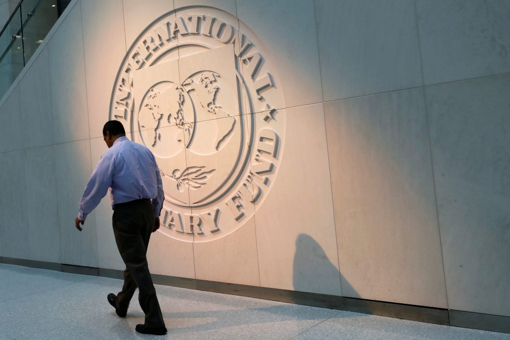 A man walks past the International Monetary Fund (IMF) logo at its headquarters in Washington. — Reuters