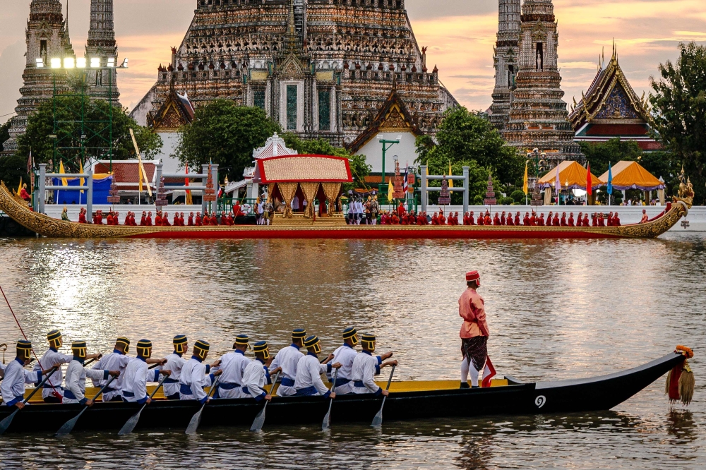 Thai oarsmen row royal barges during the Royal Barge Procession along the Chao Phraya River in front of Wat Arun in Bangkok. — AFP 