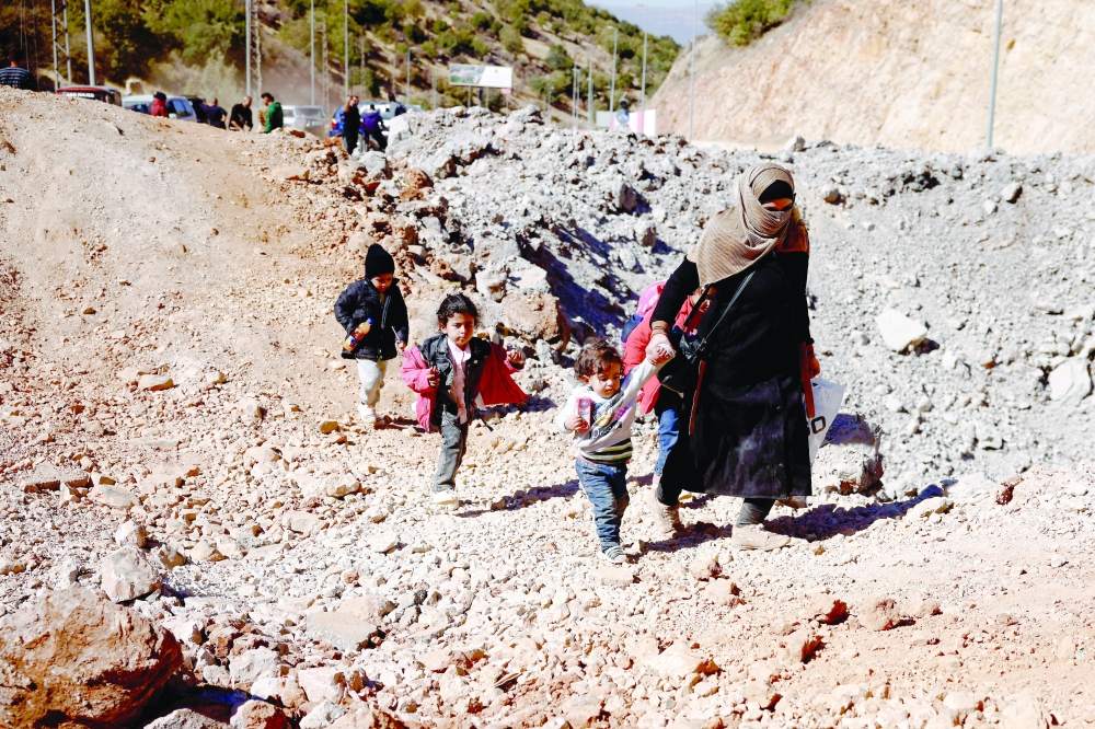 A woman walks with children while crossing from Lebanon into Syria on foot at the Masnaa border crossing. — Reuters 