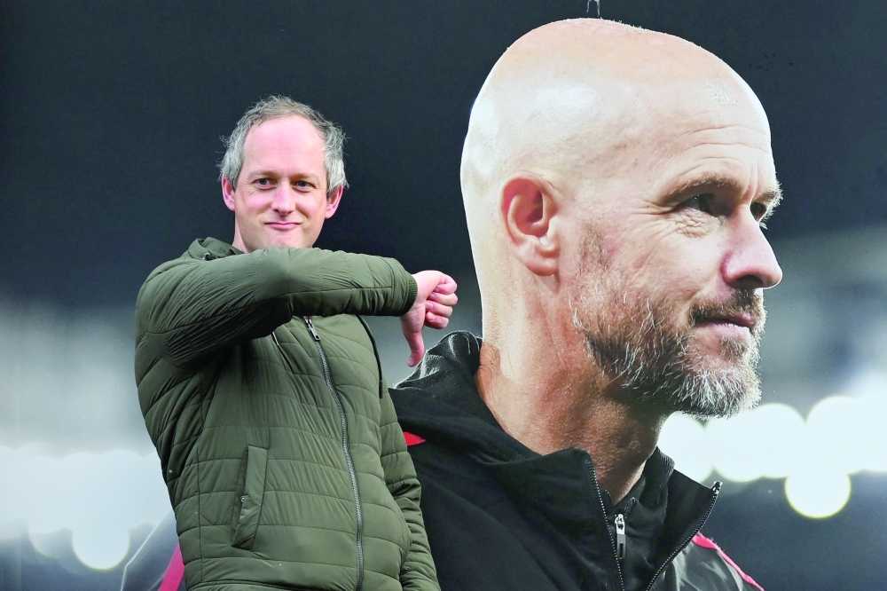 A visitor reacts as he poses in front of a picture of newly sacked Manchester United's Dutch manager Erik ten Hag, outside Old Trafford, in Manchester, north west England, on October 28, 2024. 