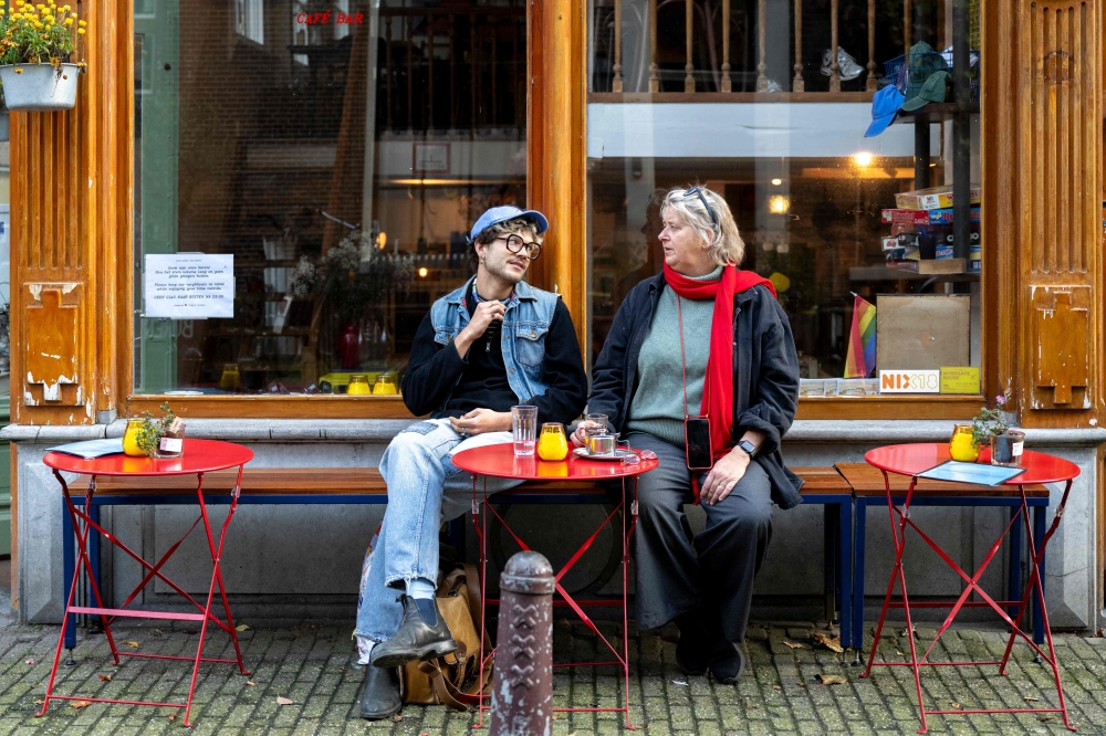 Customers sit at the terrasse of the R de Rosa cafe, in Amsterdam on October 23, 2024, as the city launches its 750th anniversary celebrations. This year, De Jordaan is the subject of a musical created to celebrate the 750th anniversary of Amsterdam, for which the festivities kick off on October 27, 2024, and run for a year.
A neighbourhood known for its popular music and outspoken residents, De Jordaan crystallises the changes that have taken place in the Dutch capital, from its working-class origins to its recent gentrification. (Photo by Nick Gammon / AFP)


