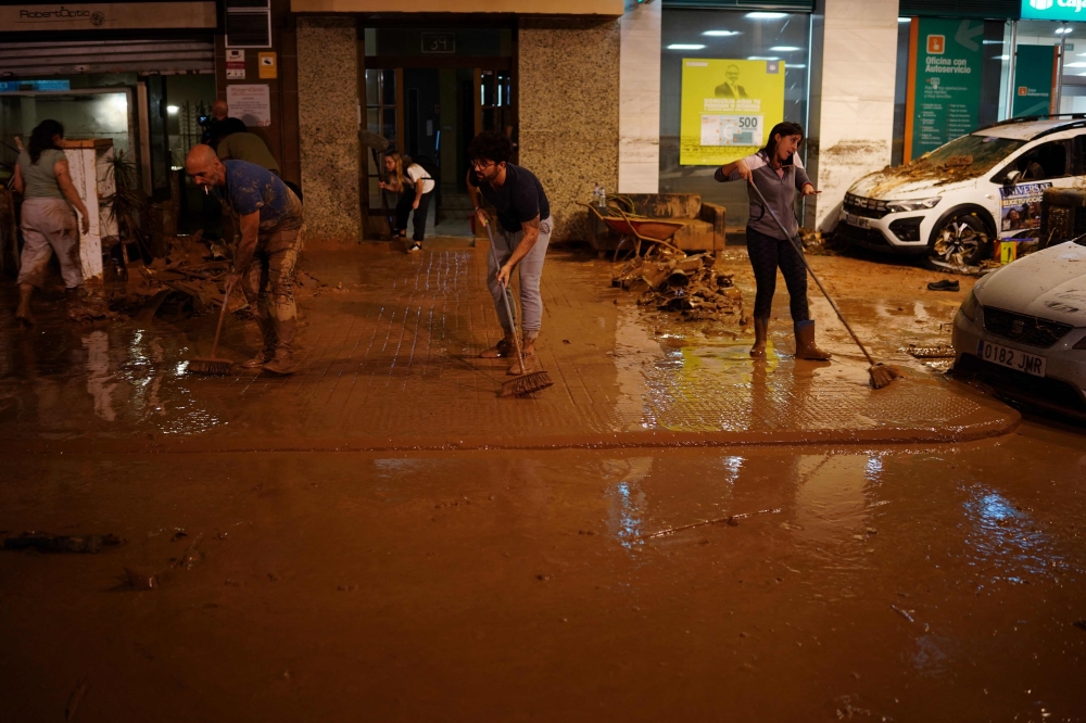  Residents clean the pavement following deadly floods in Valencia's De La Torre neighbourhood, south of Valencia, eastern Spain