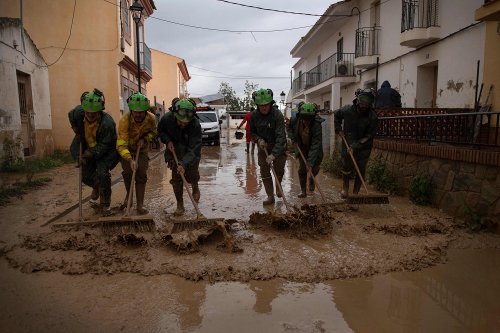 Members of the INFOCA (Andalusia Fire Prevention and Extinction Plan) clean a flooded street in Cartama, near Malaga