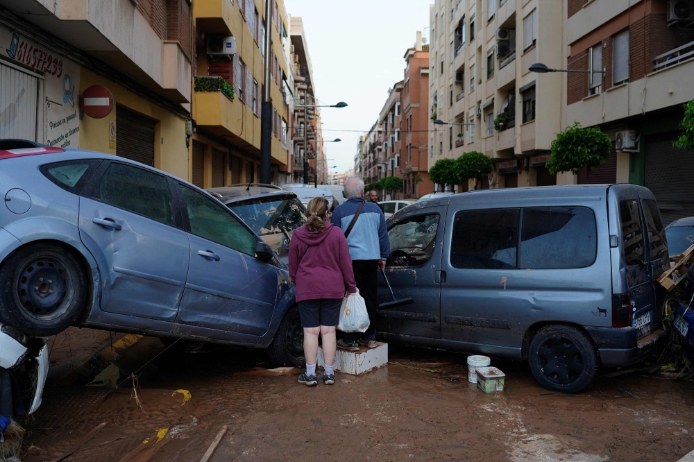 Residents stand in front of piled up cars following deadly floods in Alfafar neighbourhood, south of Valencia, eastern Spain