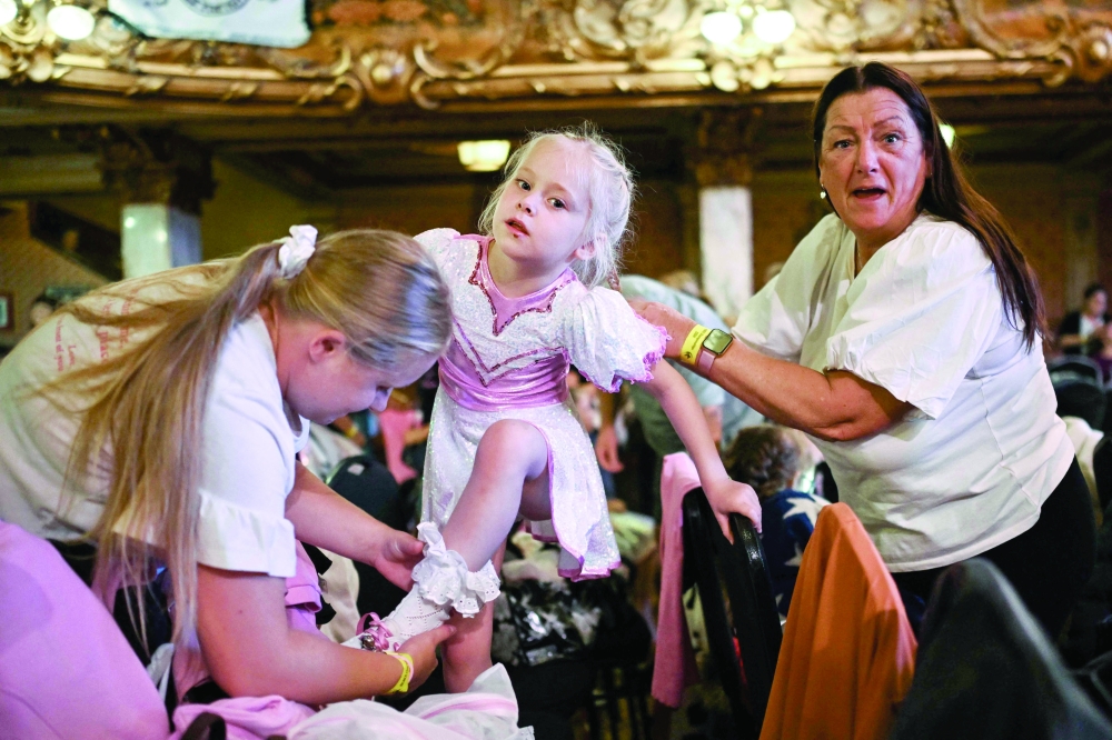 TOPSHOT - A member of the Platt Bridge Carnival Morris dancing group, performing in the Babies category, gets ready and dressed prior to compete during the REMIX End of Season Championships at the Blackpool Tower Ballroom, in Blackpool, north west of England, on September 15, 2024. Carnival Morris, also called “Fluffy” Morris, is a women and girls competitive team formation dance that is practised in the North-west of England and parts of North Wales. This traditional hobby is usually passed from mother to daughter. In fact, in the Platt Bridge group, we can find three generations of women grandmother, mother and daughter, performing for the same team in different categories.  
