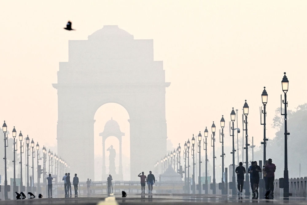 Pedestrians walk near the India gate amid smoggy conditions after Diwali
