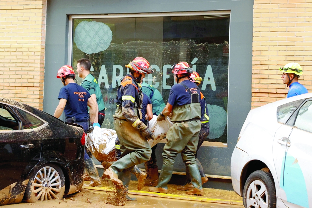 First responders carry out a body, after it was found in a parking lot, as crews look for other victims after deadly flooding in the Valencia region, in Catarroja, Spain. - Reuters