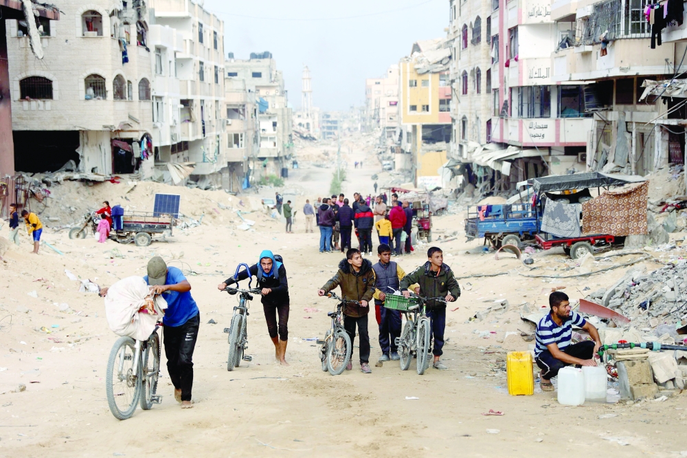 Palestinians use bicycles to navigate a devastated street in Gaza City. — AFP