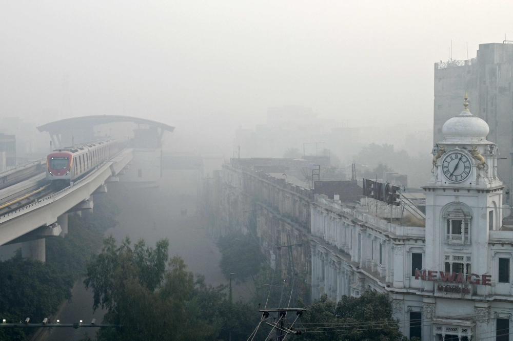 An Orange Line Metro Train (OLMT) is pictured on an elevated track amid smoggy conditions in Lahore on on November 3, 2024. Air pollution in Pakistan's second biggest city Lahore soared on November 2, with an official calling it a record high for the smog-choked mega city.  (Photo by Arif ALI / AFP)

