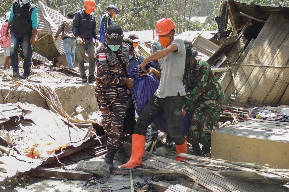 Members of a rescue team carry away body bags containing deceased people at Klatanlo village