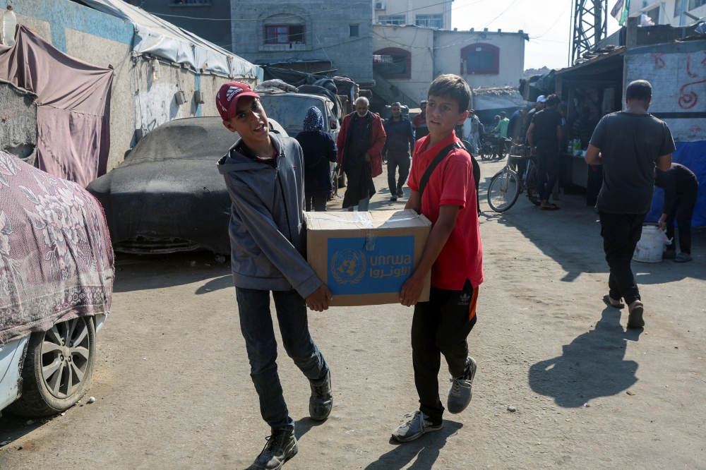 Palestinians carry an aid box distributed by the United Nations Relief and Works Agency (UNRWA), in Deir Al Balah. — Reuters file photo