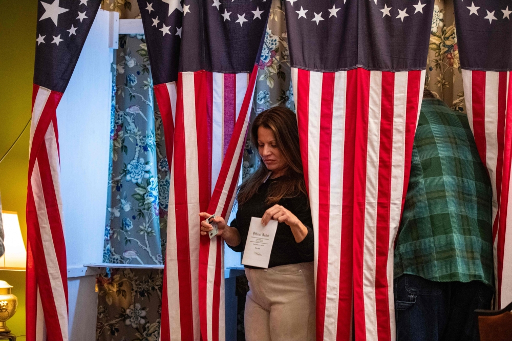 TOPSHOT - Residents of Dixville Notch cast their ballots in the US election at midnight in the living room of the Tillotson House at the Balsams Grand Resort, marking the first votes in the US election, in Dixville Notch, New Hampshire on November 5, 2024.   The six people voting in Dixville Notch, four Republican and two undeclared, kick off Election Day at the stroke of midnight.
Vice President Kamala Harris and former President Donald Trump have tied with three votes each. (Photo by Joseph Prezioso / AFP)