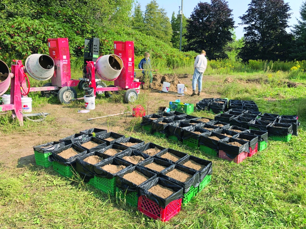 An undated photo provided by Sabrina Rondeau shows Scientists using small cement mixers to blend soils, replicating their experiment in 10 different hoop houses.