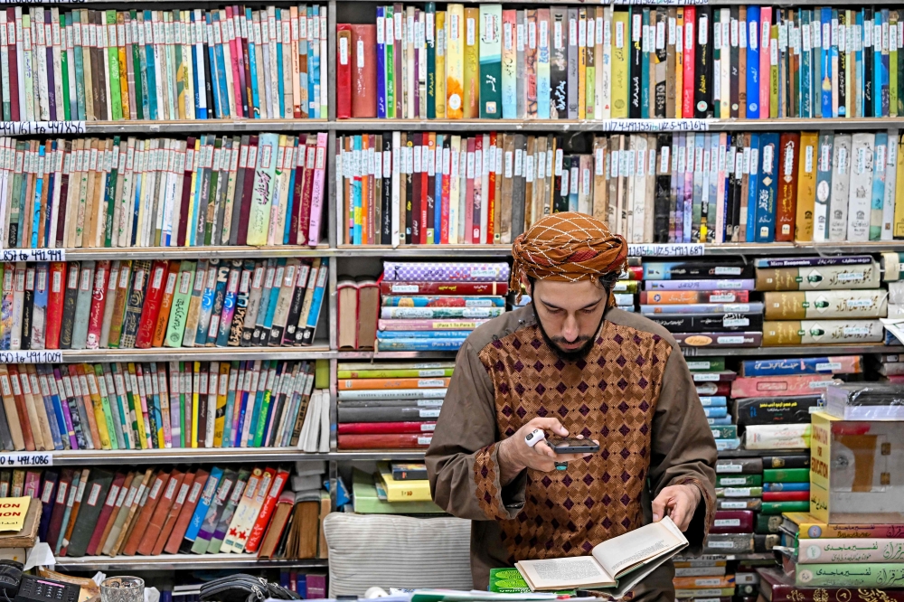 This photograph taken on October 22, 2024 shows a student taking pictures of an Urdu book at the Hazrat Shah Waliullah public library, in Urdu Bazar in the old quarters of Delhi. Urdu, spoken by many millions today, has a rich past that reflects how cultures melded to forge India's complex history. - To go with 'India-Language-History-Urdu', FOCUS by Aishwarya KUMAR and Abhaya SRIVASTAVA
 (Photo by Sajjad HUSSAIN / AFP) / To go with 'India-Language-History-Urdu', FOCUS by Aishwarya KUMAR and Abhaya SRIVASTAVA

