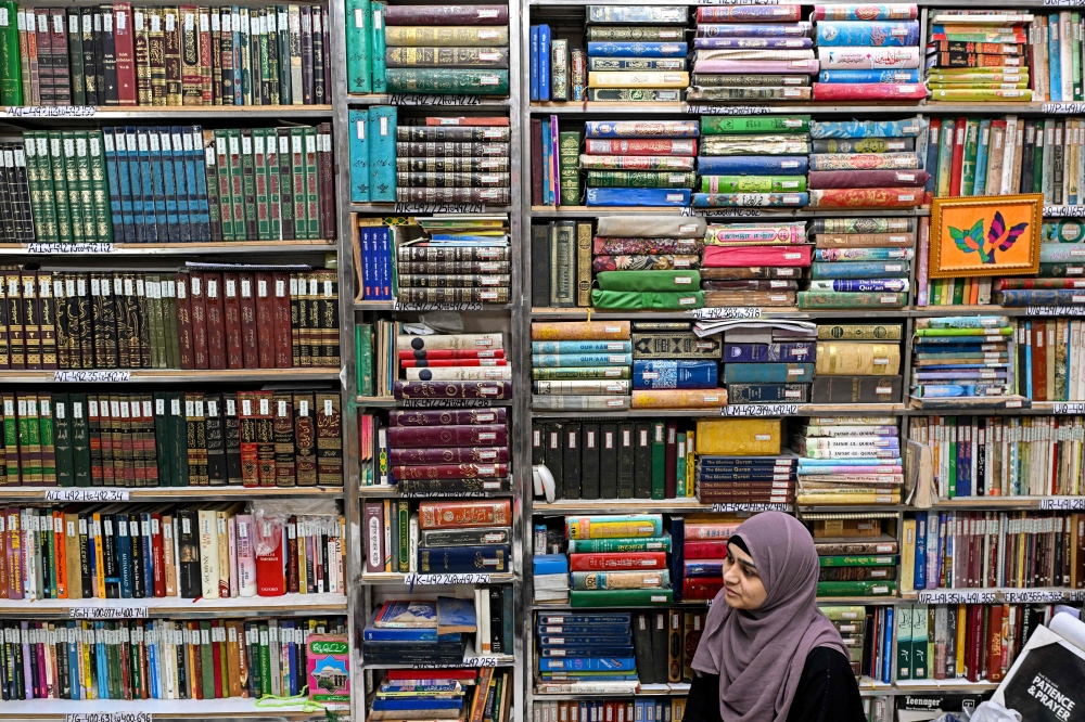 This photograph taken on October 22, 2024 shows a student sitting amid Urdu books stacked at the Hazrat Shah Waliullah public library, in Urdu Bazar in the old quarters of Delhi. Urdu, spoken by many millions today, has a rich past that reflects how cultures melded to forge India's complex history. - To go with 'India-Language-History-Urdu', FOCUS by Aishwarya KUMAR and Abhaya SRIVASTAVA
 (Photo by Sajjad HUSSAIN / AFP) / To go with 'India-Language-History-Urdu', FOCUS by Aishwarya KUMAR and Abhaya SRIVASTAVA

