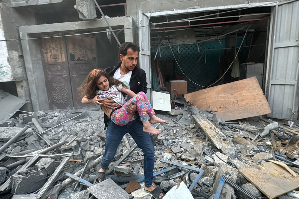 A Palestinian man carries away an injured child from a home that was hit in an Israeli strike on the Jabalia refugee camp in the northern Gaza Strip. - AFP
