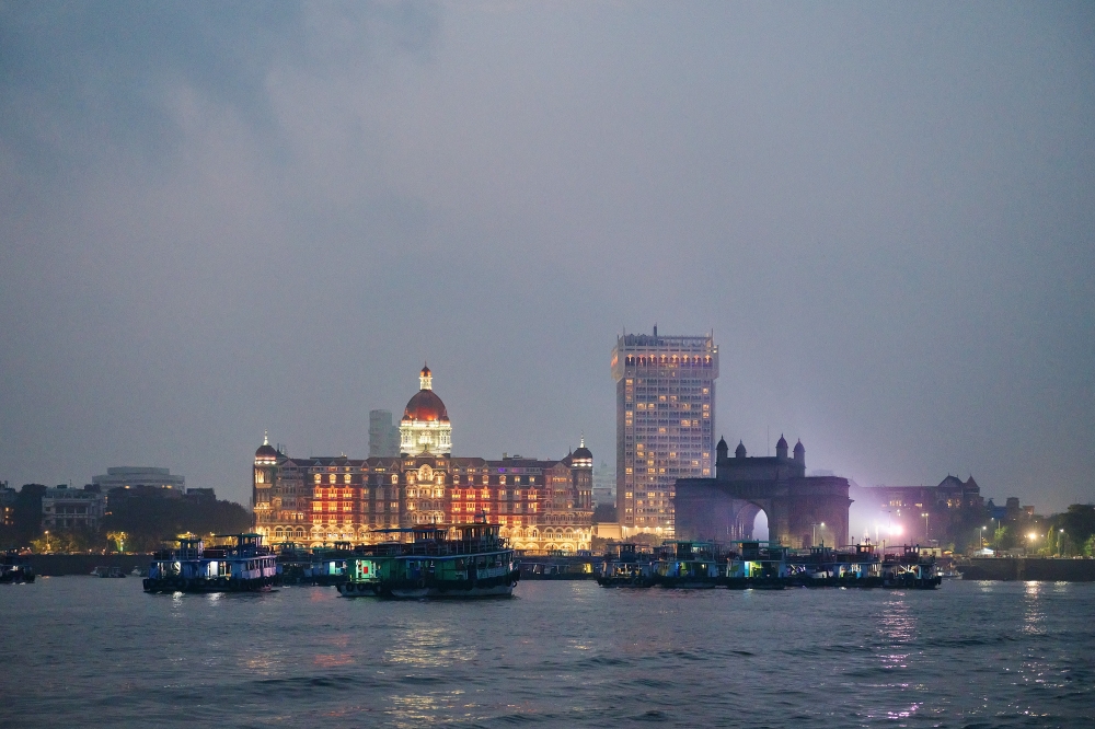 Travelers on an hourlong harbor cruise offers views of the Taj Mahal Palace Hotel, left, and the Gateway of India, right, in Mumbai, India, in October 2024. (Poras Chaudhary/The New York Times)