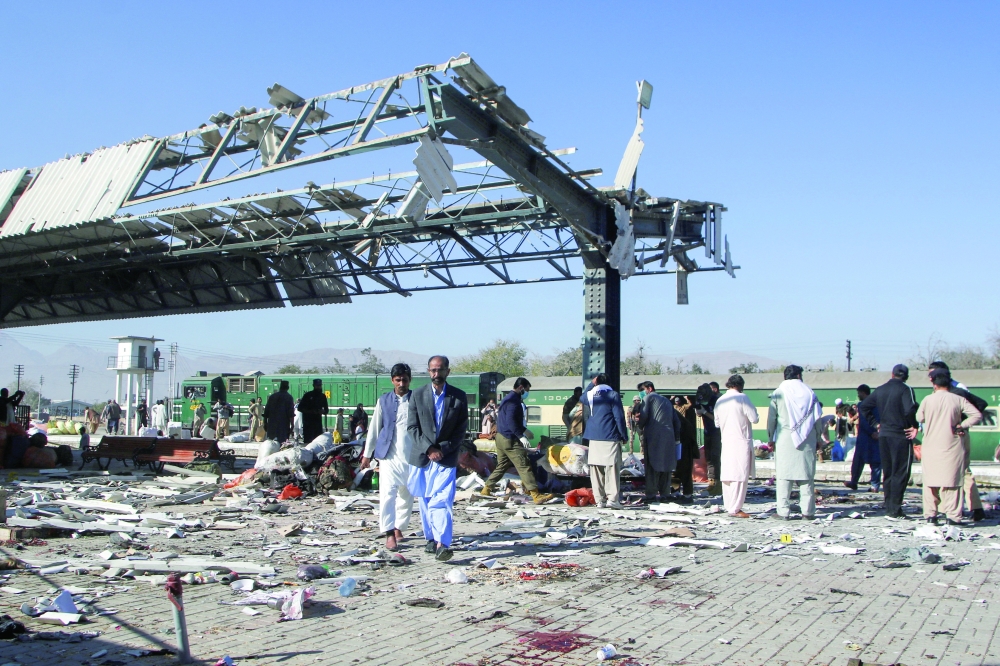 People walk amid the debris after a bomb blast at a railway station in Quetta, Pakistan. — Reuters