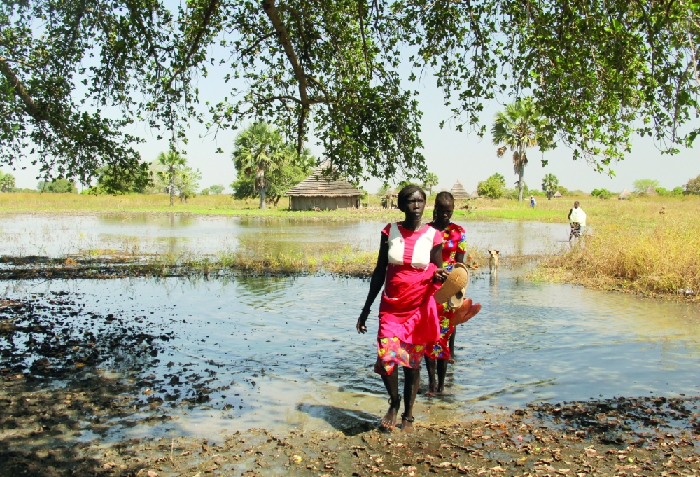 A displaced woman crosses a flooded area in South Sudan