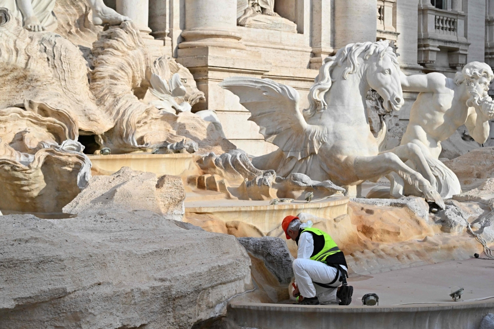 A person is seen working at the renovation of the Trevi Fountain on November 9, 2024. A  temporary suspended walkway was inaugurated today to allow visitors to see the fountain closer during renovation works.

 The work -- including cleaning stones in the lower part of the monument and grouting joints -- should be completed by the end of the year, the council said. Limited groups of visitors will be allowed to cross the fountain on a raised walkway while the maintenance is carried out. (Photo by Andreas SOLARO / AFP)

