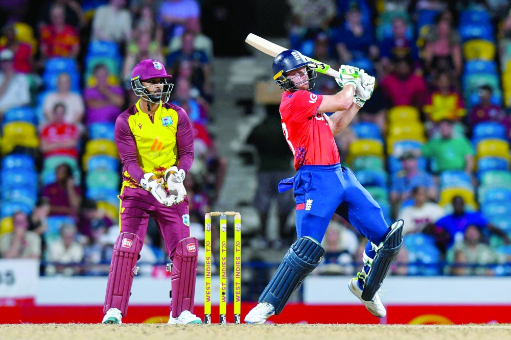 Jos Buttler (R) of England hits 6 to bring up his 50 and Nicholas Pooran (L) of West Indies watches during the second T20i match between West Indies and England at Kensington Oval in Bridgetown, Barbados, on November 10, 2024.  (Photo by Randy Brooks / AFP)

