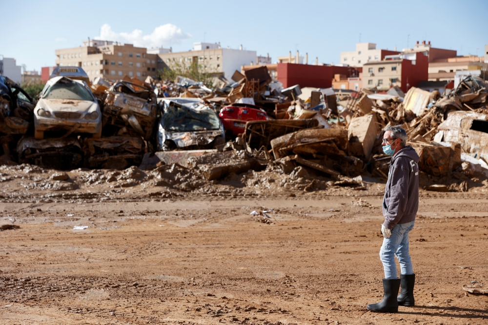 A man stands next to vehicles damaged in deadly floods in Catarroja, Valencia, Spain. — Reuters