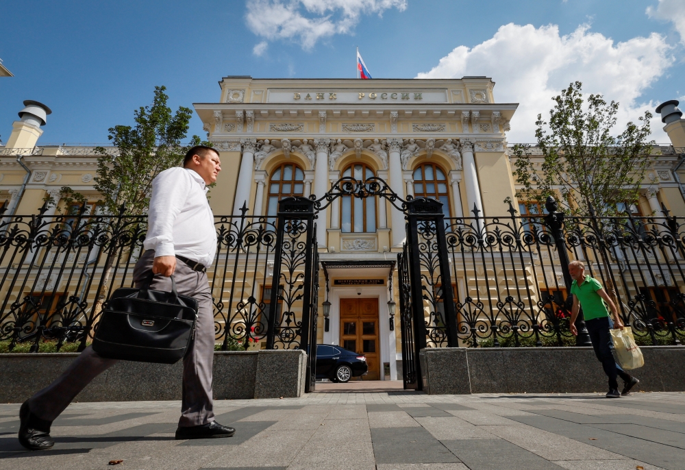 Pedestrians walk past the Central Bank headquarters in Moscow, Russia. — Reuters