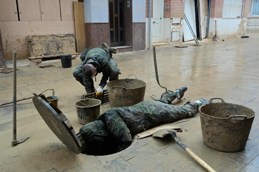 Soldiers evacuate mud from a sewer in Paiporta, south of Valencia, eastern Spain, on Wednesday in the aftermath of deadly flooding. Spain closed schools and evacuated residents as heavy rains lashed the country on November 13, two weeks after its worst floods in a generation killed more than 200 people.

