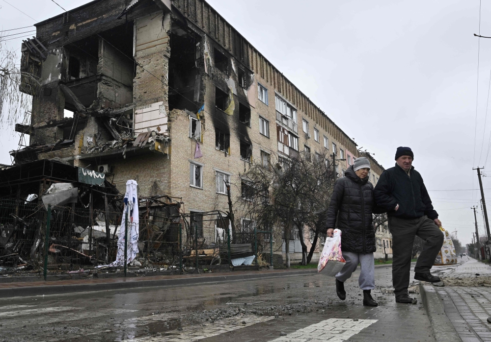 Pedestrians walk past a damaged residential building in the village of Gostomel, close to Kyiv. — AFP file photo