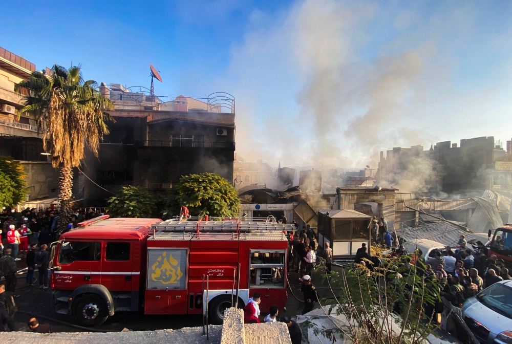 Smoke rises as people gather at a damaged site after what Syrian state news agency said was an Israeli strike in Damascus suburb of Mazzeh, Syria. — Reuters 