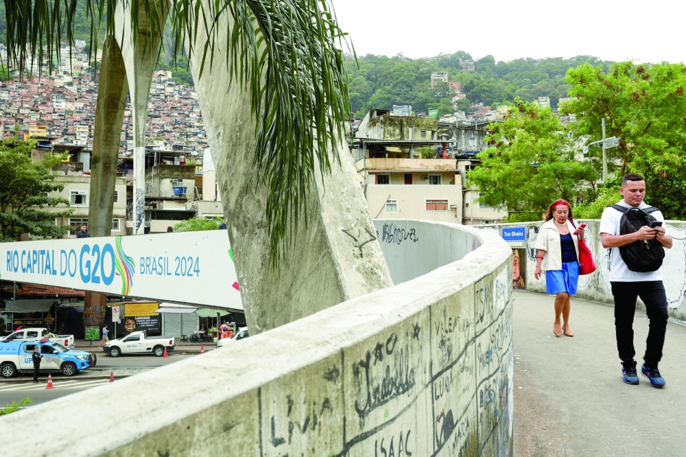 People walk near a banner with the Rocinha slum in the background, ahead of G20 Summit, in Rio de Janeiro, Brazil. — Reuters