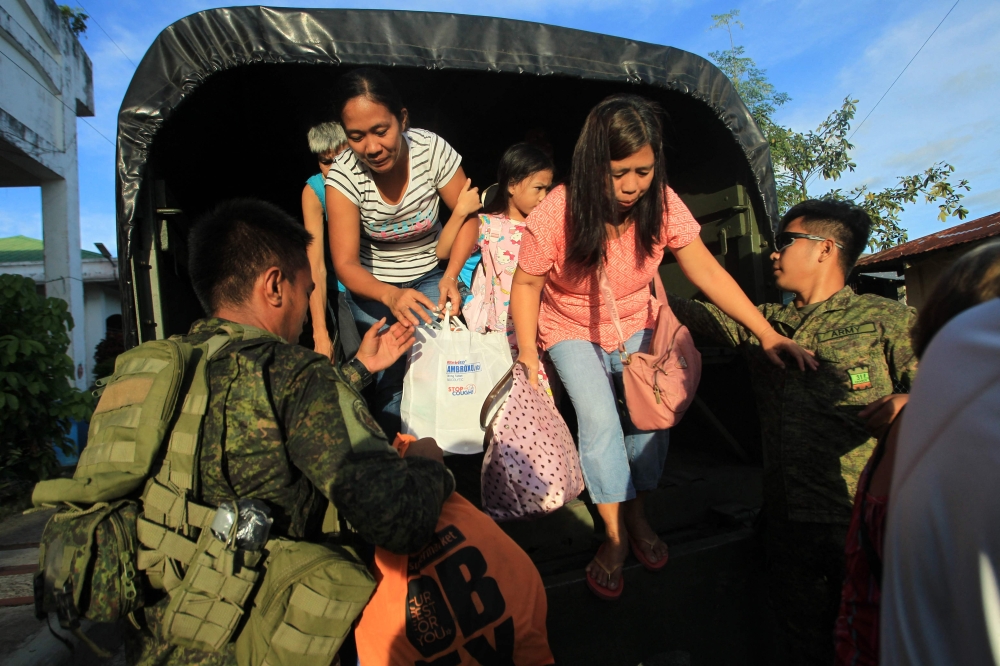 Residents get off a truck after the local government implemented a preemptive evacuation in Daraga, Albay on November 15, 2024